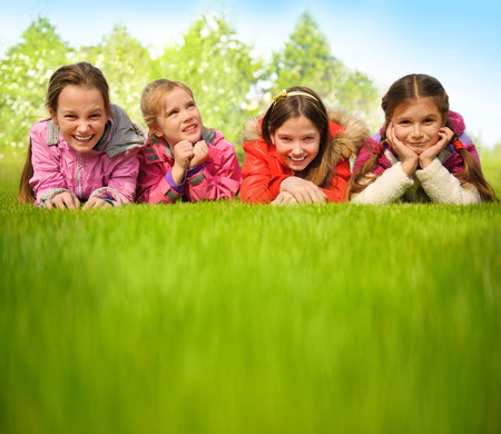 Happy group of girls lying on a green grassの写真素材