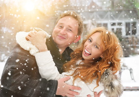 Winter couple piggyback in snow smiling happy and excited  Beautiful young couple at backyard of their houseの写真素材