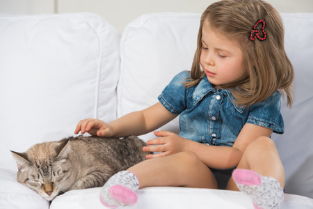 Cute little girl hugging tabby cat with love, looking at cat.の写真素材