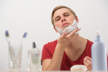 Closeup portrait of young man applying shaving creamの写真素材