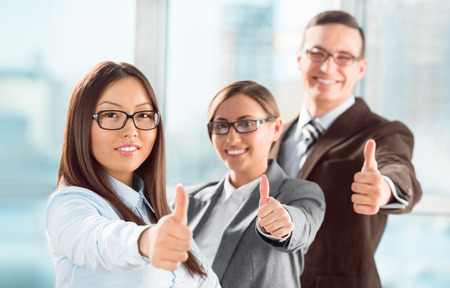 Successful young business people showing thumbs up signの写真素材