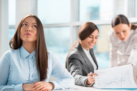 Beautiful young business executive with colleagues discussing in the backgroundの写真素材