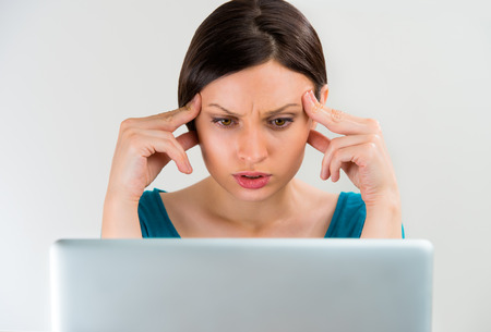 Young sad serious woman thinking, working on laptopの写真素材