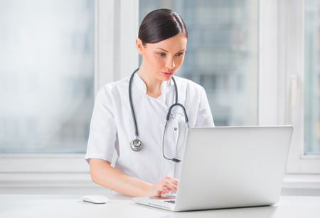 Portrait of a female doctor using her laptop computer at clinicの写真素材