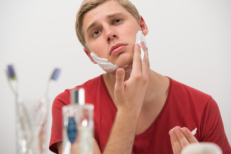 Closeup portrait of young man applying shaving creamの写真素材