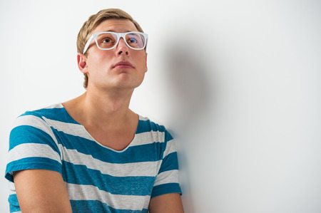 Portrait of a happy young man wearing glasses looking upwards in thoughtの写真素材