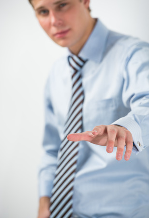 Young positive business man touching virtual button. Editable imageの写真素材