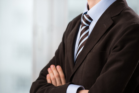 Closeup of torso of confident business man wearing elegant suit with hands foldedの写真素材