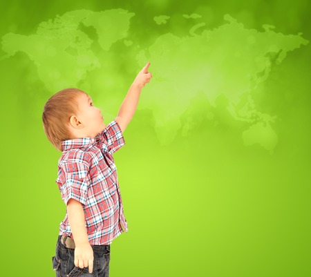 Happy little boy pointing up to world mapの写真素材