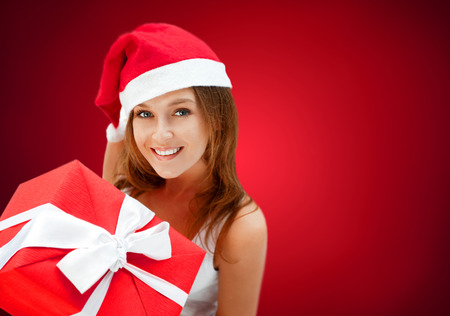 Young happy girl in Christmas hat. Holding huge christmas giftの写真素材