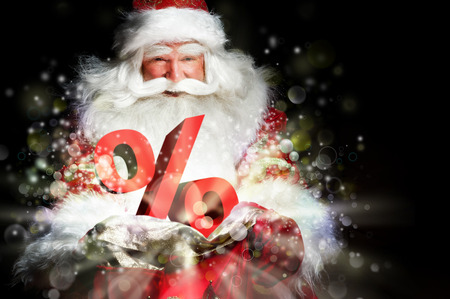 Santa Claus holding his bag and smiling. Lights and sparks are flying from the bag. Diccount symbol sign in front of Santaの写真素材
