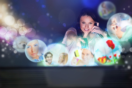 Young woman watching tv at home. Holding remote control and choosing channel. の写真素材
