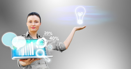 Business woman presenting technological solutions with her laptop and virtual iconsの写真素材