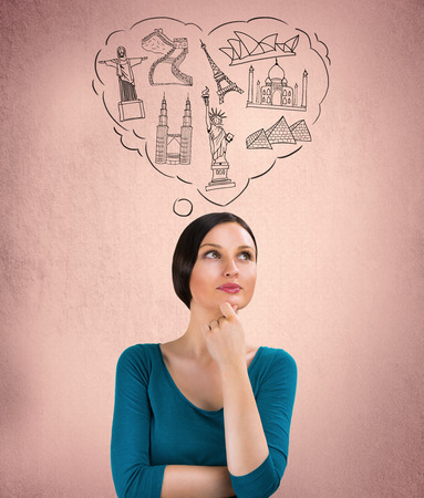 Young pretty woman dreaming about her vacation. Famous touristic destinations symbols are drawn overheadの写真素材
