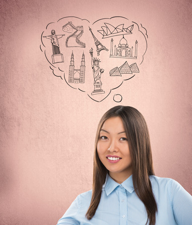 Young pretty woman dreaming about her vacation. Famous touristic destinations symbols are drawn overheadの写真素材