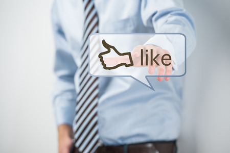 Business man touching social media button with thumb up symbol on a virtual screenの写真素材