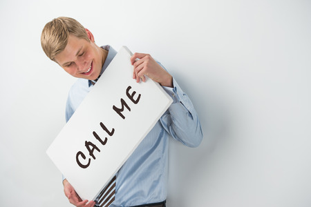 Handsome businessman showing "call me" text on a billboardの写真素材
