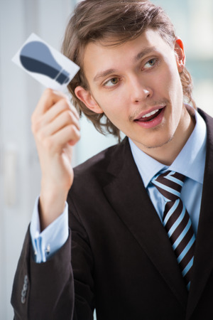 Detail shot - business man showing business card with idea symbolの写真素材