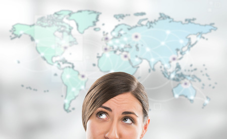 Portrait of young woman standing in front of big world map. Server locations and actual online connections are displayed on virtual map. Hosting provider concept.の写真素材