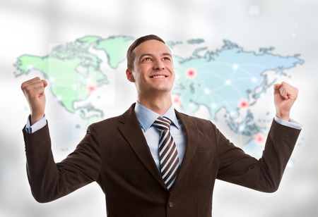 Portrait of young man standing in front of big world map. Server locations and actual online connections are displayed on virtual map. Hosting provider concept.の写真素材