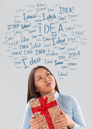 Gift Idea concept. Young business woman with gift and  idea signs overheadの写真素材