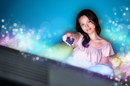 Young woman watching TV sitting on the beanbag at homeの写真素材