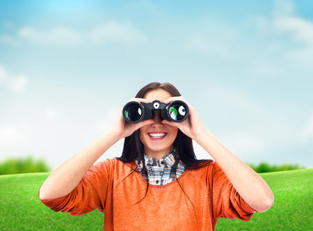 Woman looking through binoculars at summer parkの写真素材