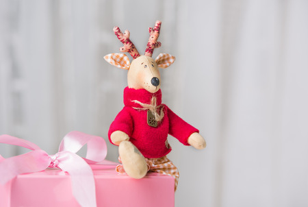 Handmade toy vintage Christmas deer sitting on the pink gift boxの写真素材