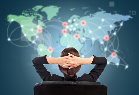 Attractive brunette young woman in futuristic interface sitting in front of world map with glowing hot points location and connection lines.の写真素材