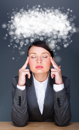 Beautiful European young solid businesswoman sitting with glasses against grey background and thinking about something. Blank cloud balloon with copyspace overheadの写真素材
