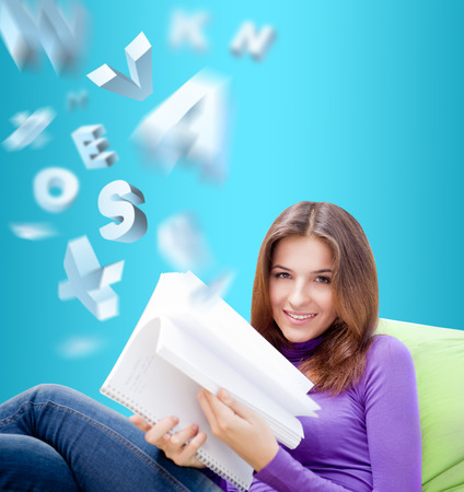Young pretty woman reading book at home. Self education or cultural leisure conceptの写真素材