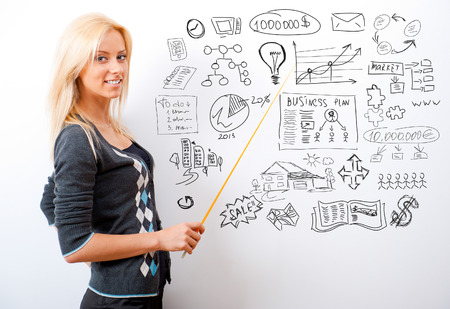 Portrait of young teacher pointing on white marker board in modern educational centerの写真素材