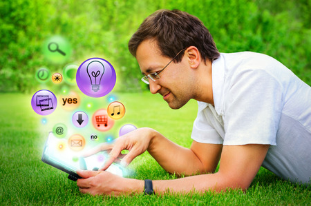 Adult man using his tablet computer at countryside. Different icons appearing from touchscreenの写真素材