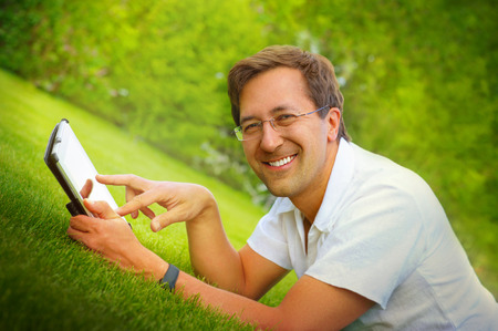Adult man working with tablet computer outdoor in parkの写真素材