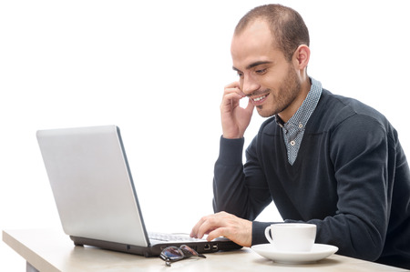 A young man sitting in front of a laptop isolatedの写真素材