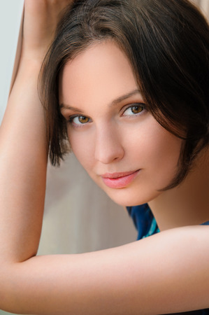 Portrait of relaxed young lady smiling while leaning on a windowの写真素材