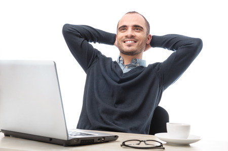 Young businessman looking up relaxing with hands behind head and day dreaming at officeの写真素材