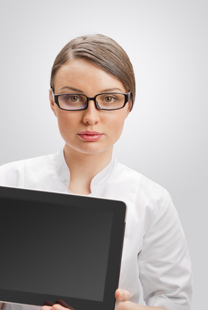 Young woman doctor in white coat  holding digital tablet pcの写真素材