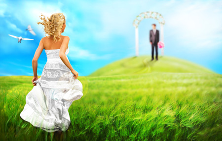 Young bride running to her groom to altar across the meadow. Wedding conceptの写真素材
