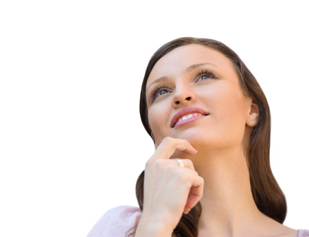 Beautiful young woman daydreaming over white background with finger on chinの写真素材