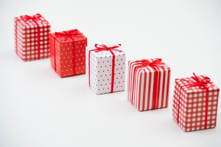 Gift boxes with xmas presents wrapped in red paper with ornament on white background. Lots of copyspaceの写真素材