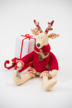 Handmade toy vintage Christmas deer sitting on light with gift boxの写真素材