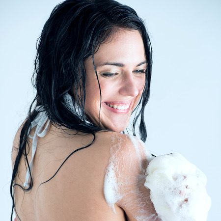 Young woman washing body with shower gel at home or hotel