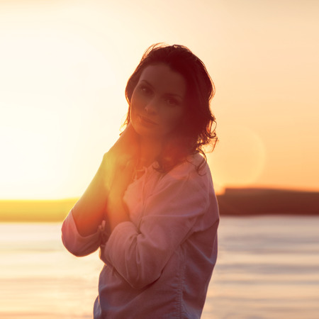 Young woman walking on beach under sunset light. Vintage style photoの写真素材