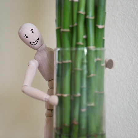 Wooden man standing at home and looking out of the tree. People emotions concept. Drawn facesの写真素材