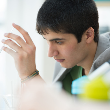 Male student with group of classmates on background working at the school or college or university laboratory during chemical lessonの写真素材