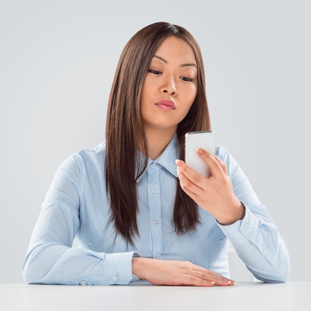 Beautiful happy business woman reading a text message sitting at her deskの写真素材