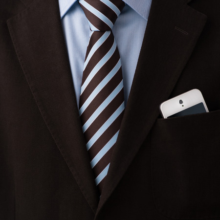 Closeup of torso of confident business man wearing elegant suit and mobile phone at pocketの写真素材