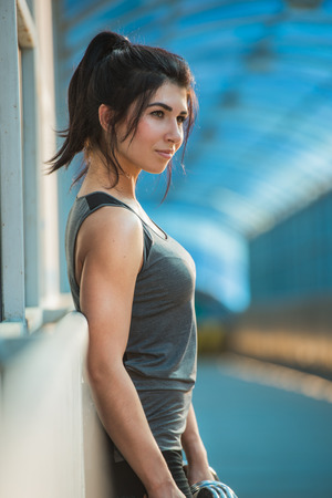 Athletic woman pumping up muscles with dumbbells outdoors in the cityの写真素材