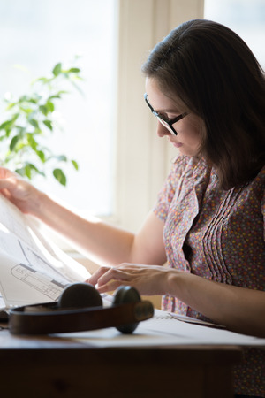 Woman working at home with laptop and architecture planの写真素材